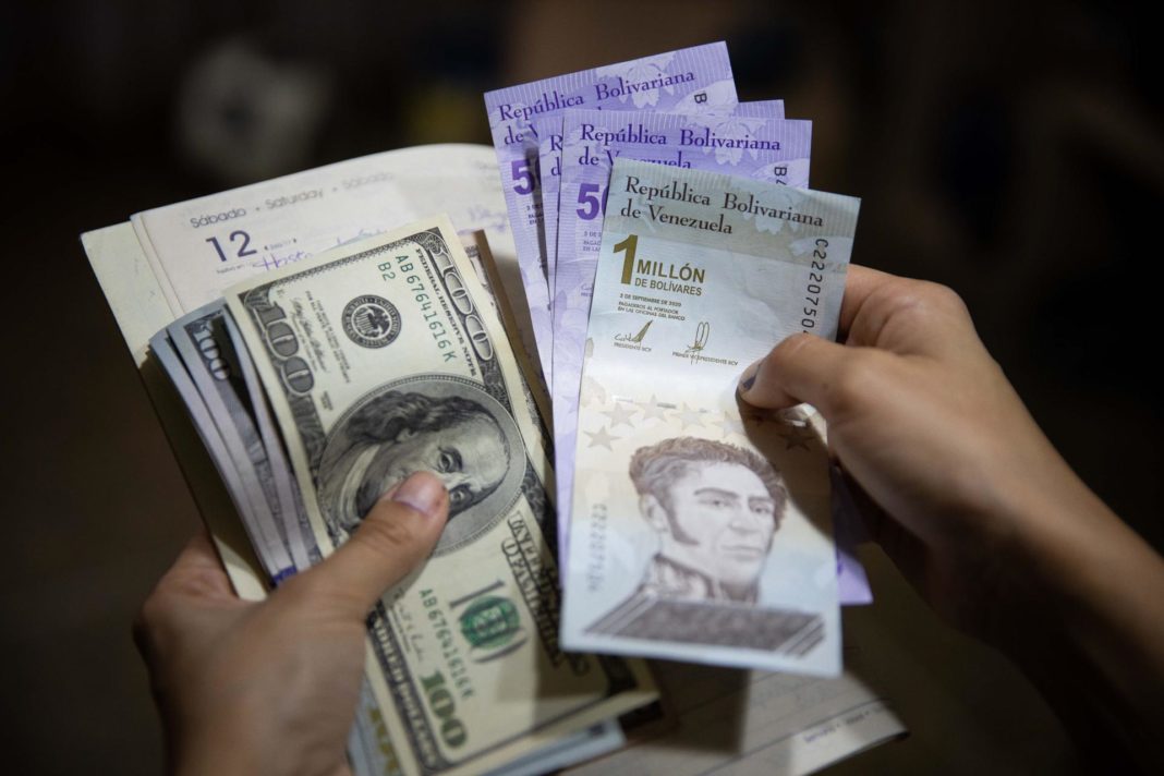 Una persona sostiene un fajo de billetes de dólar y bolívares, en una fotografía de archivo. EFE/Rayner Peña R
